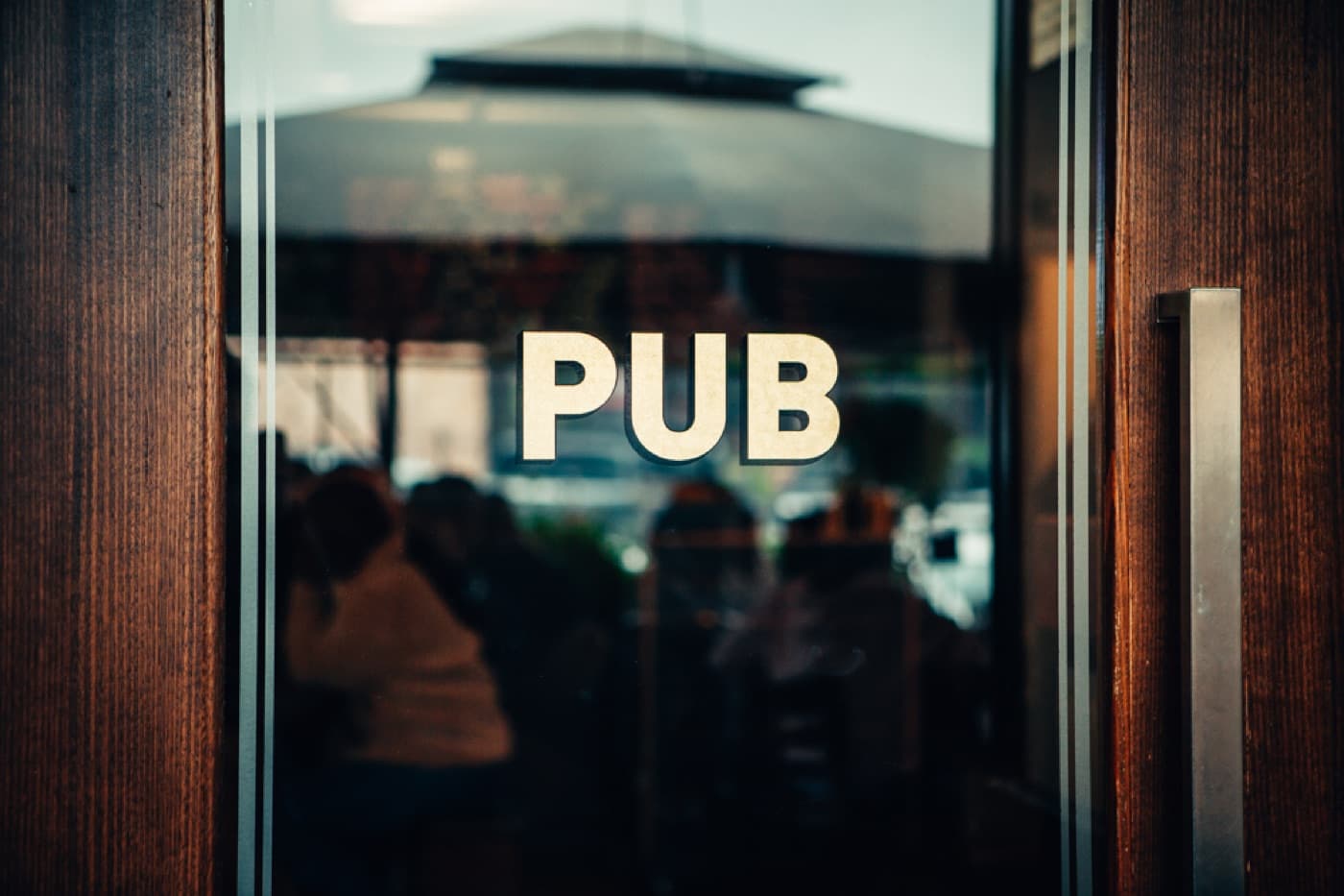 The pub's front door on the corner, PUB lettered across the glass